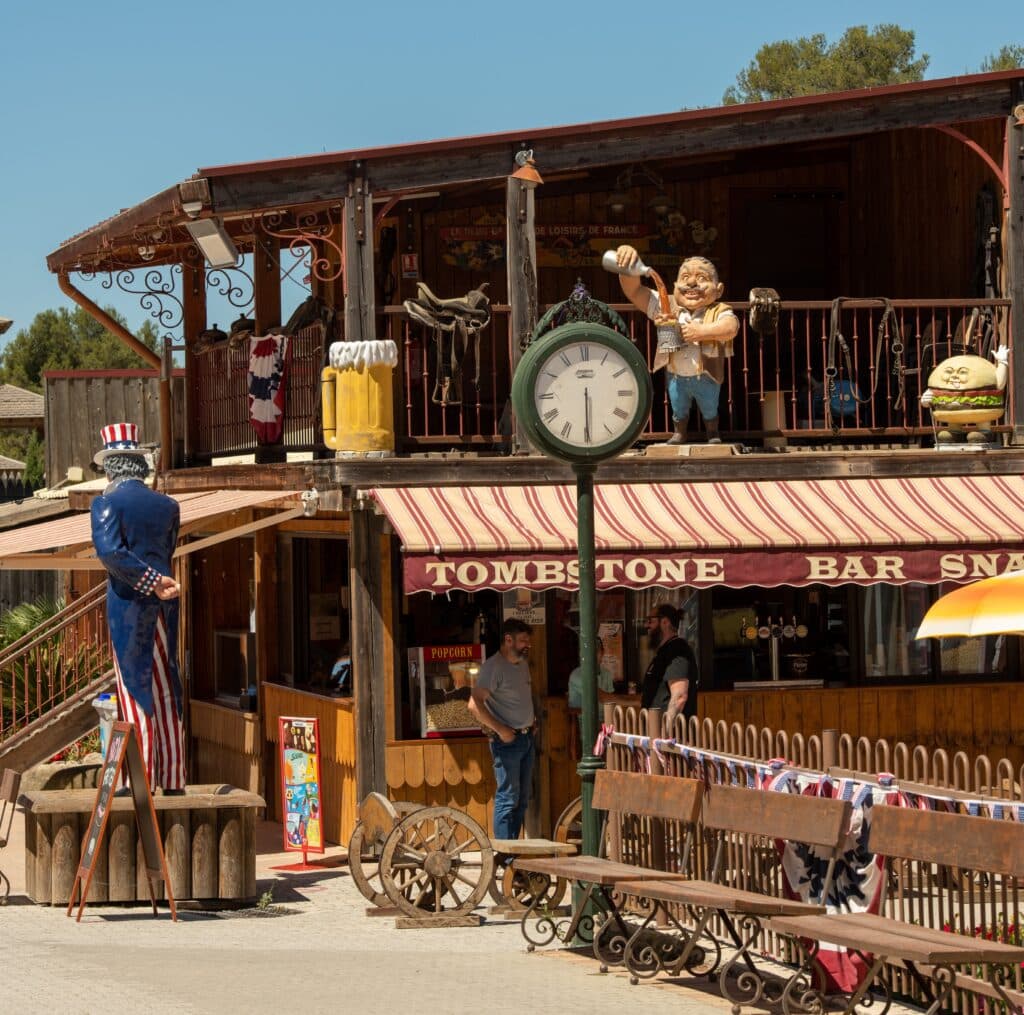 OK CORRAL offre une ambiance Far West immersive avec son bar à thème "Tombstone", idéal pour une journée en famille au parc d’attractions dans le Sud de la France. Les visiteurs peuvent découvrir des décorations authentiques et profiter d'animations en plein air tout en savourant des collations.

OK CORRAL, parc à thème familial, présente un décor western captivant autour du bar "Tombstone", parfait pour les familles et les enfants. Les sculptures et l'architecture évo